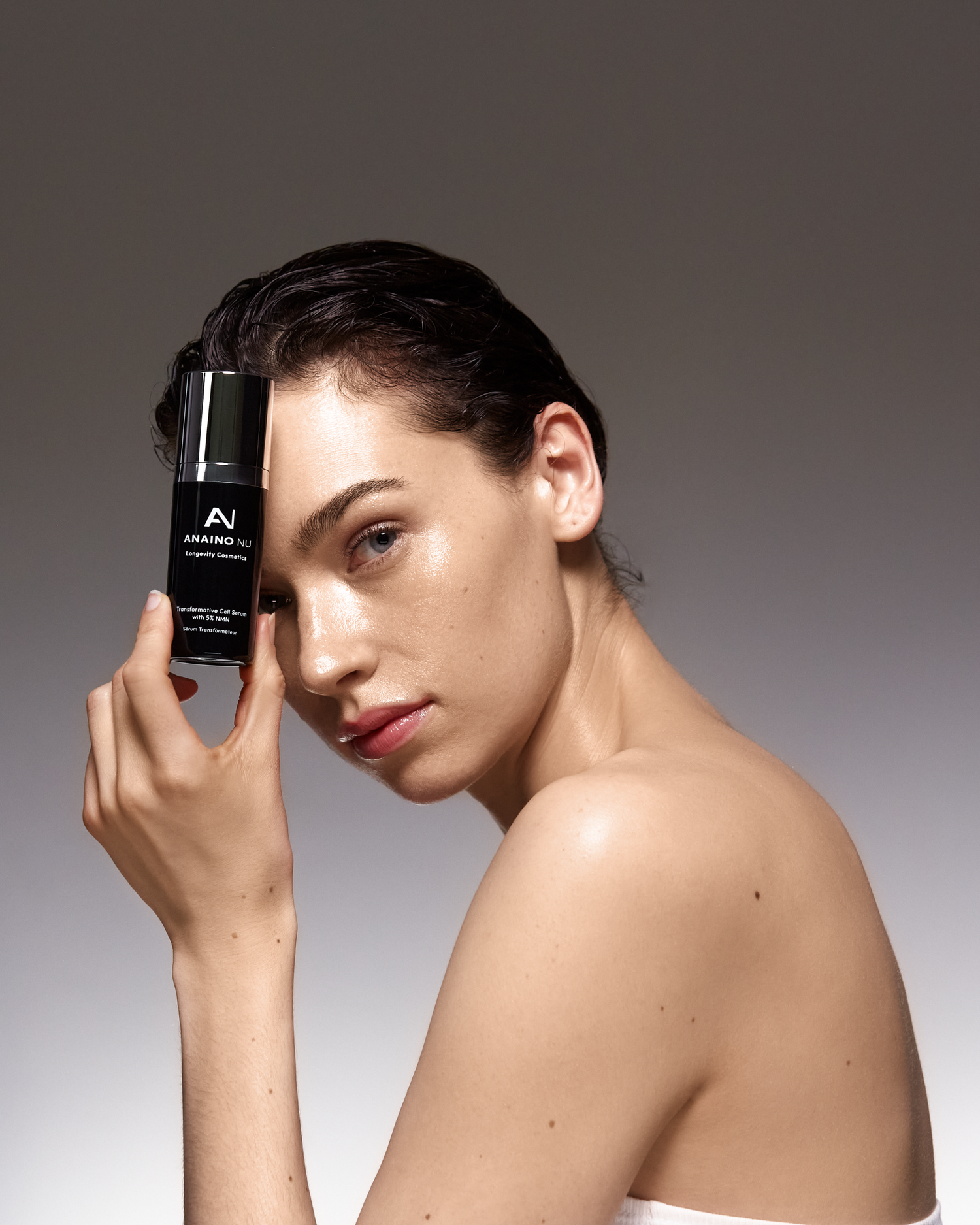 Eine Frau mit einem Hautprodukt in der Hand. Anaino Nu. Ein Anti-Falten Serum, das den Ursachen von Falten entgegenwirkt.